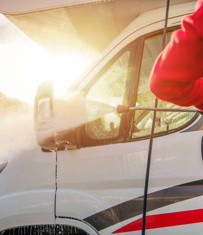 Caucasian Men Washing Camper Van RV Using Pressure Washer. After Season Motorhome Maintenance.